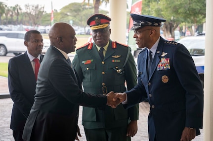 A man in military uniform shakes hands with another man in civilian attire.