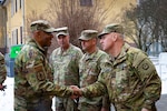 Men in camouflage uniforms shake hands.