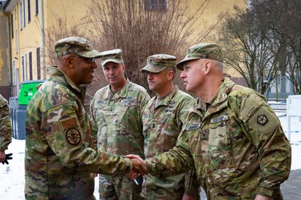 Men in camouflage uniforms shake hands.