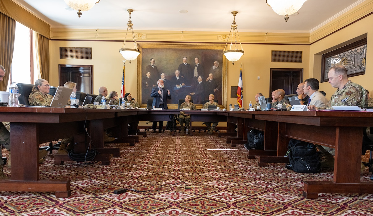 People sit at a u-shaped table at the Utah state capitol building.