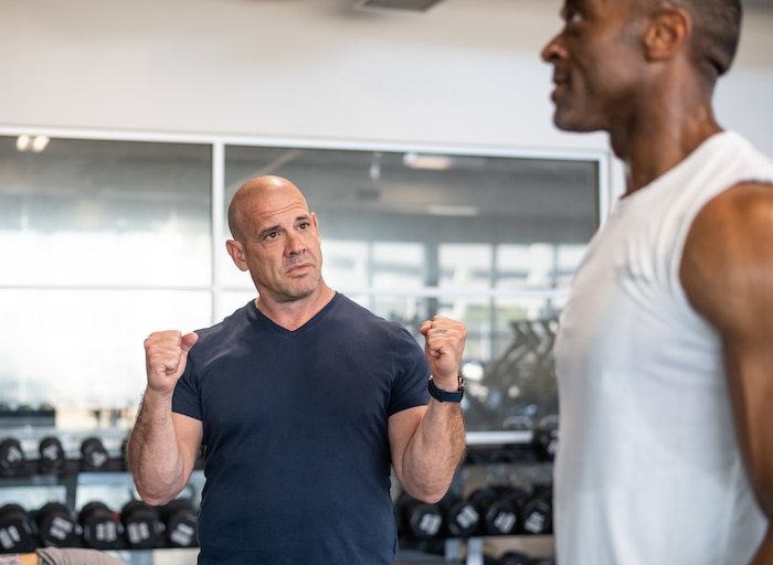 John Hofman, SSC’s certified strength and conditioning specialist, discusses the proper form for a standing barbell overhead press with Tyrone Roach, engineering specialist at the Aerospace Corporation, at the Los Angeles Air Force Base Fitness Center. Photo by Van D. Ha