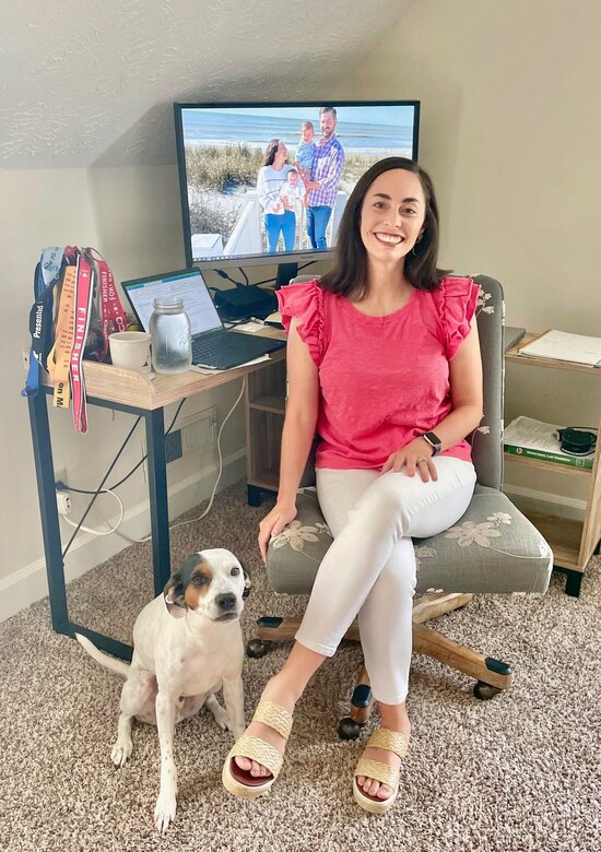 Woman working at a desk with her dog sitting next to her.