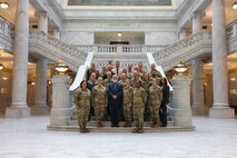 A group of people in uniform pose for a photo inside the Utah State Capitol building.