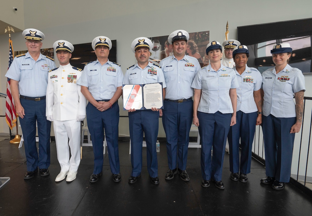 U.S. Coast Guard Rear Adm. Douglas Schofield, Seventh District commander, presents the Coast Guard meritorious unit commendation award to the plank owner members of Marine Safety Unit Lake Worth at Port of Palm Beach, Florida, July 19, 2024. The ceremony established MSU Lake Worth as one of 18 marine safety units in the Coast Guard to have a junior officer in command. (U.S. Coast Guard photo by Petty Officer Eric Rodriguez)