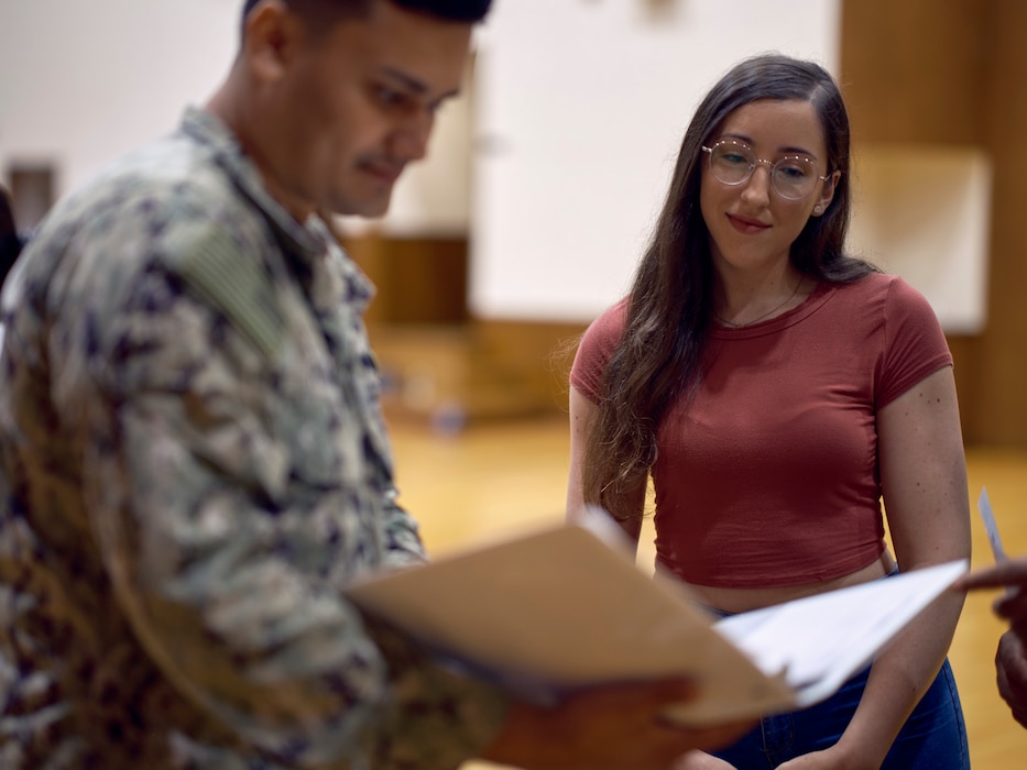 Isabel Sabae, a military spouse volunteer, confirms her processed Emergency Evacuation Package with Damage Controlman 2nd Joshua Roman from Commander, Fleet Activities Yokosuka's Emergency Operations Center during a simulated Emergency Evacuation July 18, 2024 in the installation's C-2 Auditorium as part of Exercise Citadel Pacific 2024.