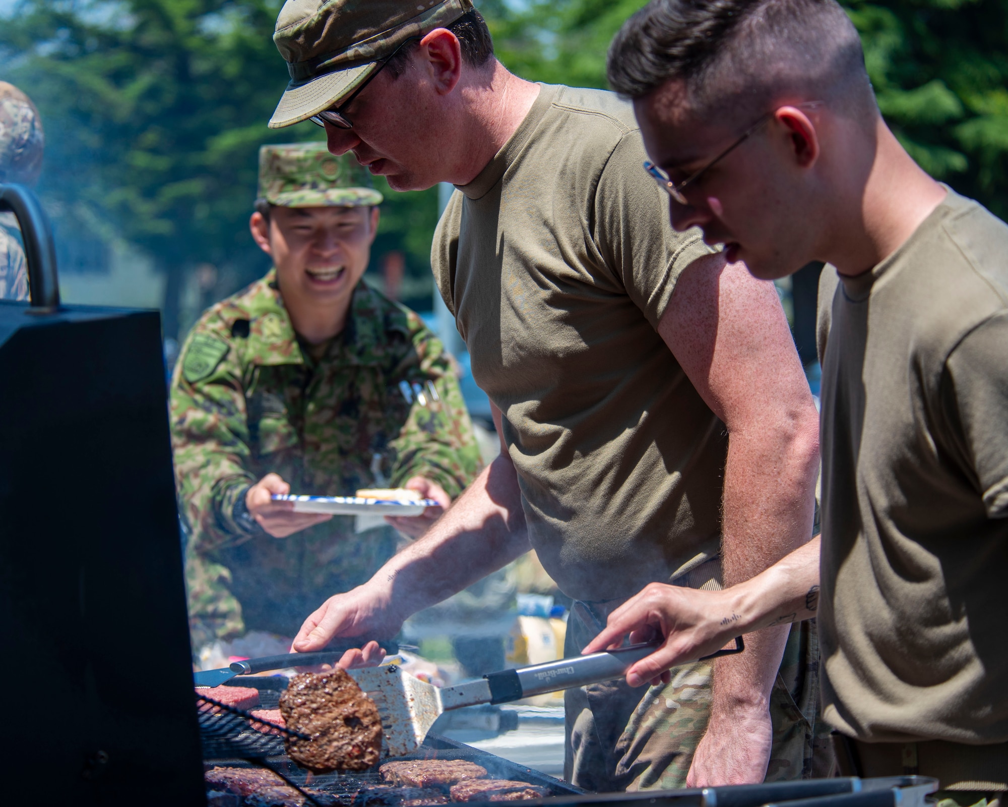 U.S. Air Force Airmen assigned to the 35th Communications Squadron cook burgers for Japan Ground Self-Defense Force soldiers as part of a JGSDF Basic English Training Course tour at Misawa Air Base, Japan, July 18, 2024.