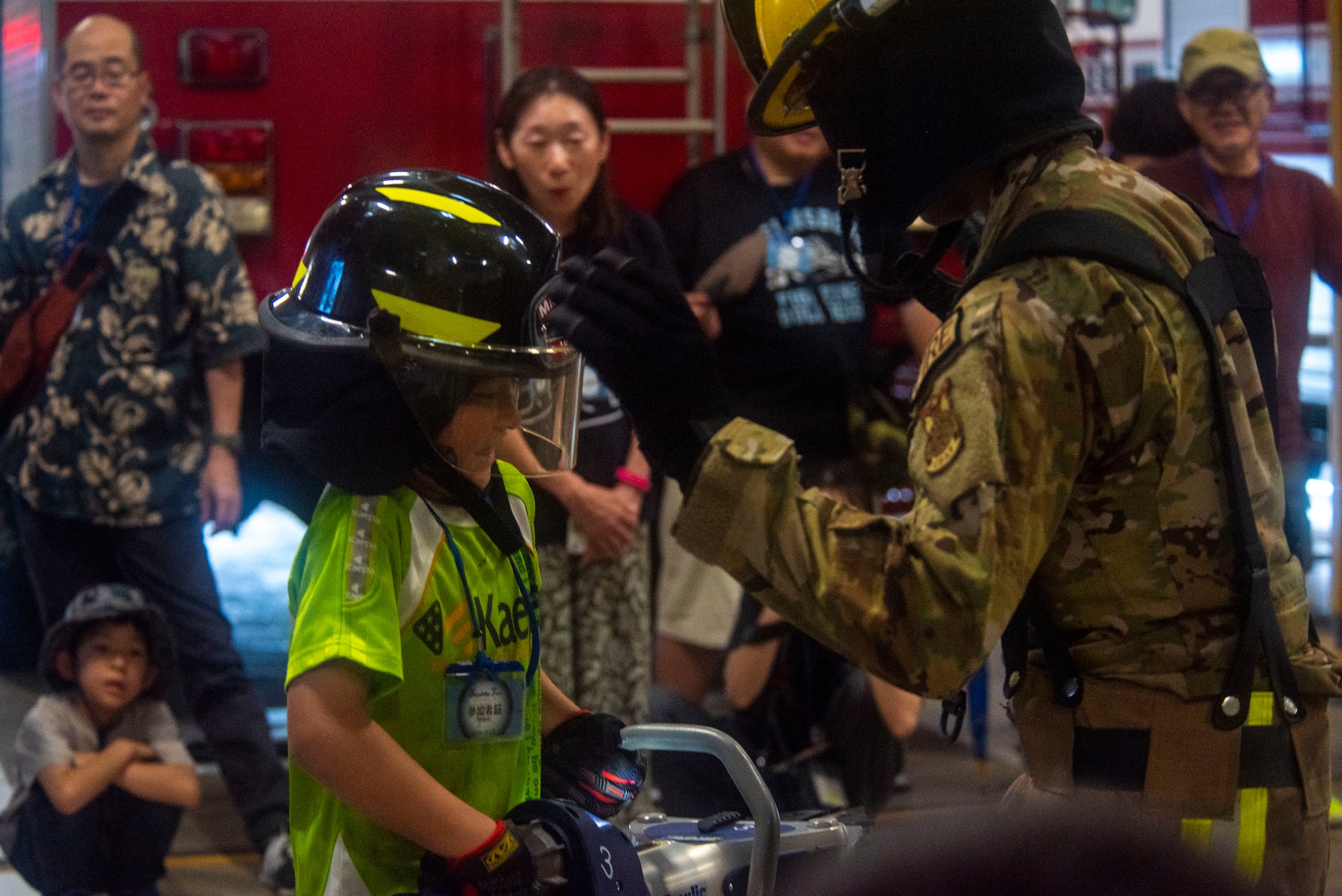A Misawa Friendship Tour participant attempts to hold a hydraulic rescue tool “Jaws of Life” while U.S. Air Force Airman 1st Class Malik Williams, right, 35th Civil Engineer Squadron firefighter, stands by for support at Misawa Air Base, Japan, July 19, 2024.