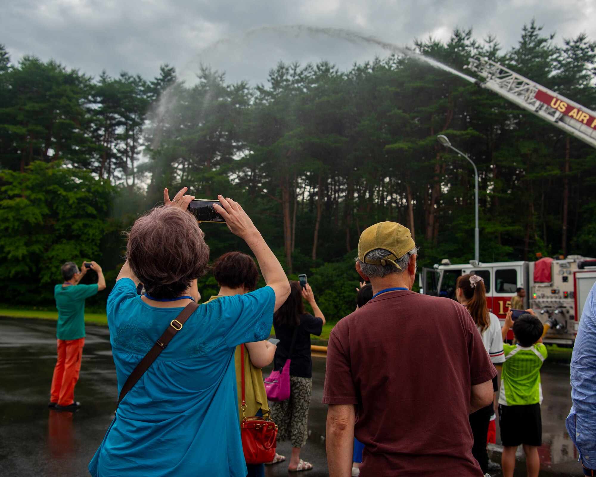 A Misawa Friendship Tour participant takes a video of a fire truck spraying water at Misawa Air Base, Japan, July 19, 2024.