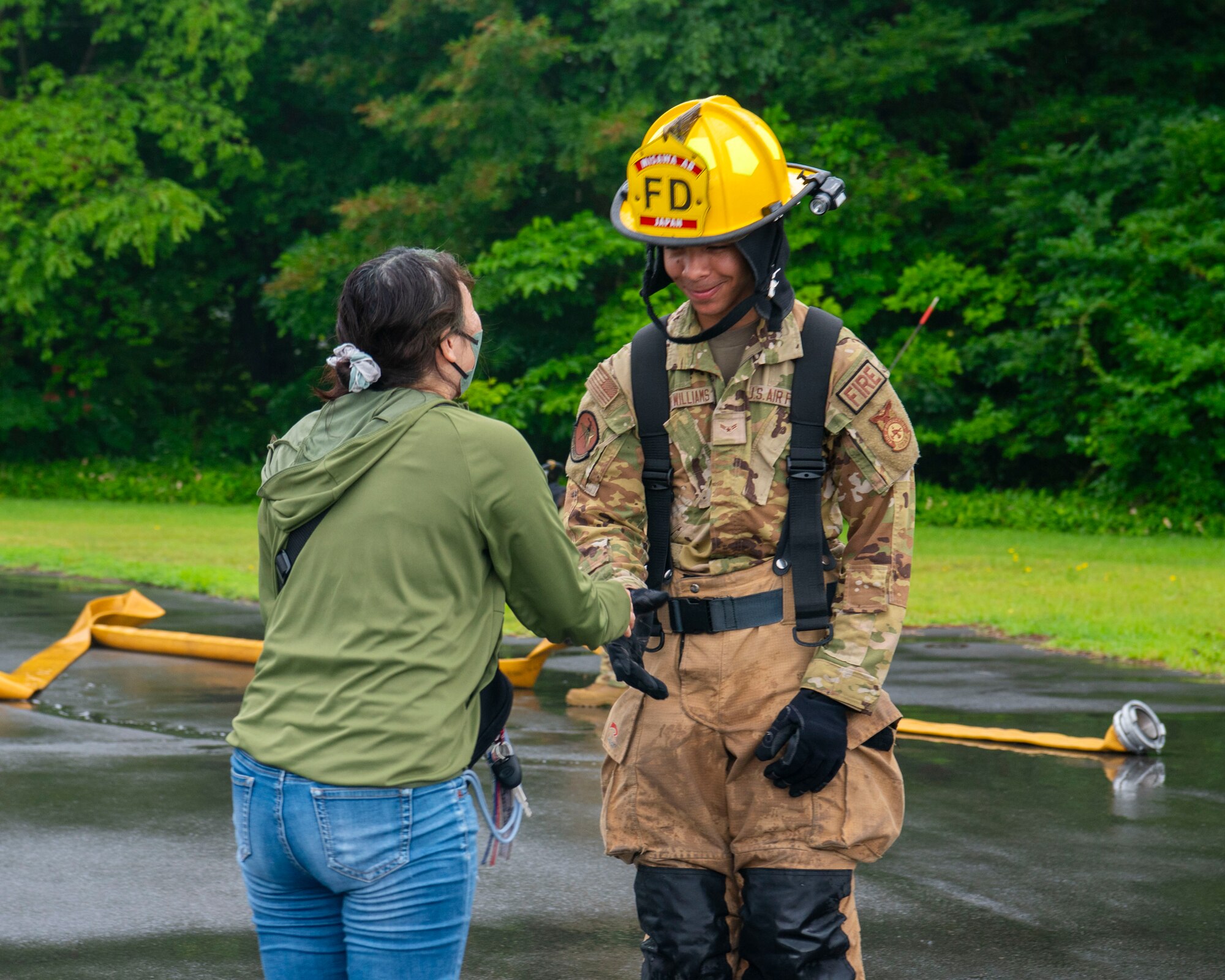 U.S. Air Force Airman 1st Class Malik Williams, right, 35th Civil Engineer Squadron firefighter, shakes hands with a Misawa Friendship Tour participant at Misawa Air Base, Japan, July 19, 2024.