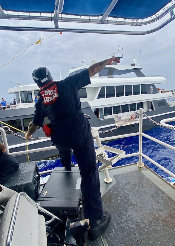 A crewman aboard USCGC Oliver Henry (WPC 1140) tosses a heaving line to set up a tow to the crew of the 150-foot 497-ton motor yacht Black Pearl 1, located approximately 200 nautical miles west of the Republic of Palau on July 21, 2024, after responding to a distress call. The 11-person yacht crew, who reported a locked rudder and flooding in the bilge, was assisted by Oliver Henry's crew with dewatering and damage control as they headed toward Palau in 25 mph winds and 4 to 6-foot seas. (U.S. Coast Guard photo by Ensign Mikasa Lierman)