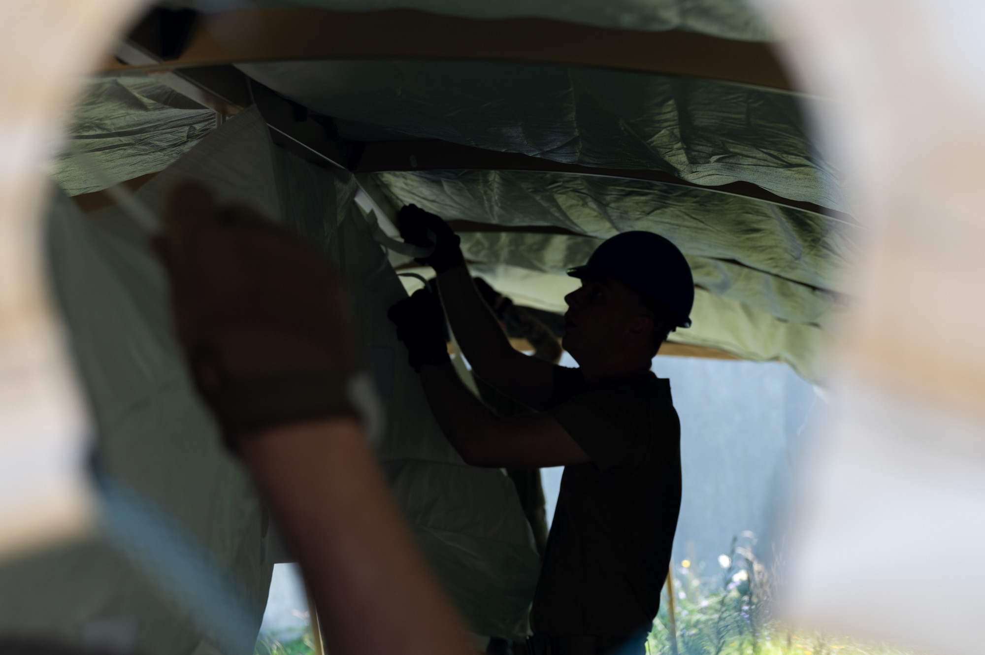 An Airman sets up a curtain in a tent.
