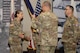 Four uniformed Soldiers pass a unit flag during a change of command ceremony