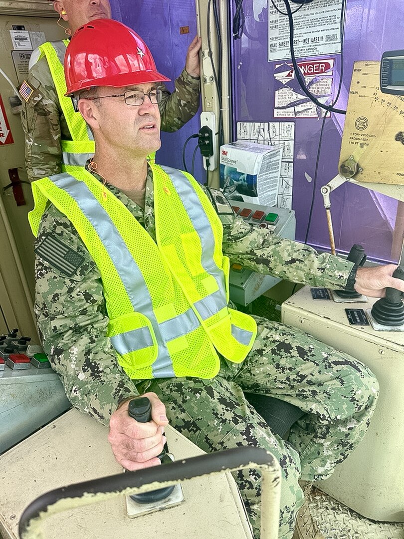 A man in U.S. Navy camouflage operates a crane