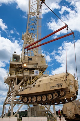 An 80-ton gantry crane lifts an Army tank.
