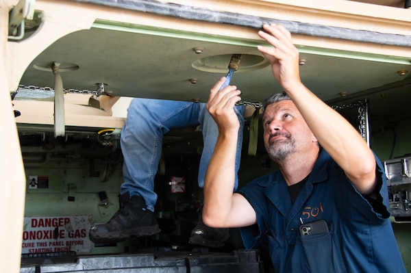 A man uses a paintbrush on a U.S. Army asset