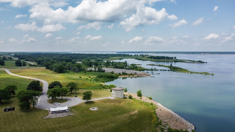 A large body of water is on the right and a large patch of grass is on the left with blue sky in the background.