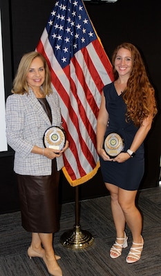 Naval Information Warfare Center (NIWC) Atlantic Information Technology (IT) Specialist Melissa Earhart, left, and Scientist Samantha Meyer pose with their Excellence in Service Awards from the New Orleans (NOLA) Federal Executive Board (FEB) following an award ceremony June 13 at the U.S. Department of the Interior Bureau of Safety and Environmental Enforcement NOLA Office. Earhart and Meyer, co-leads for the NIWC Atlantic NOLA detachment STEM program, won the Community Service Team Award for STEM.