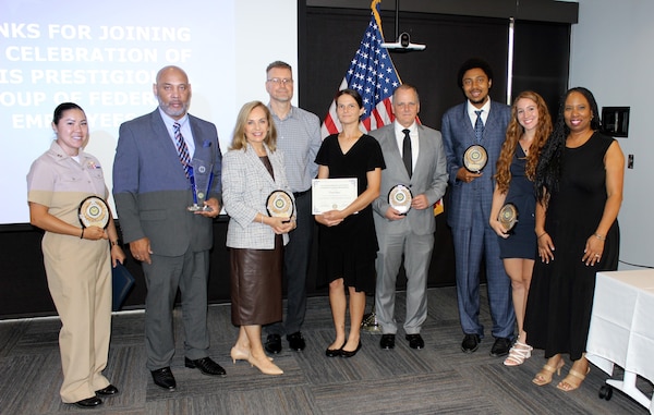 Employees of Naval Information Warfare Center Atlantic display their Excellence in Service Awards from the New Orleans Federal Executive Board (FEB) following an award ceremony June 13 at the U.S. Department of the Interior Bureau of Safety and Environmental Enforcement New Orleans Office. The Excellence in Service Awards Program honors outstanding federal employees who have performed exceptional and meritorious work, demonstrating high standards of performance in the federal government. NIWC Atlantic’s NOLA detachment submitted eight individual nominations and one team nomination, of which, five won in their category and the others received honorable mentions. From left to right: Lt. Angie Hung, who accepted for Information Systems Technician Chief Thomas Whipple (not in photograph), Military Excellence; Jessie James Lee, Outstanding Leadership – Senior Manager/Director (both local and national); Melissa Earheart, Community Service Team for STEM; Brian Spragins, Honorable Mention for Mission Support Excellence; Devon Vance, Honorable Mention for Leadership Excellence – Team Lead; Donald Zuvich, Mentor of the Year and Team Excellence; Michael Sinegar, Call to Service; Samantha Meyer, Community Service Team for STEM; and Monica Weber, who represented the Navy Personnel and Pay (NP2) Team for Team Excellence.