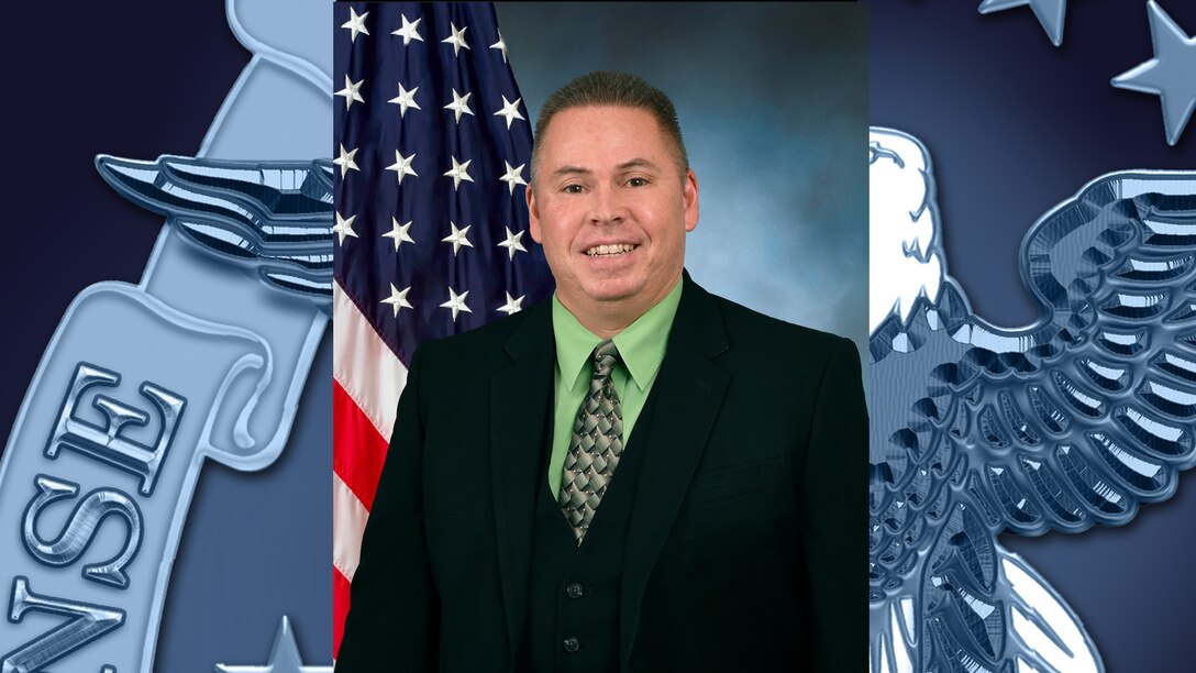 Official photo of employee with flag in background