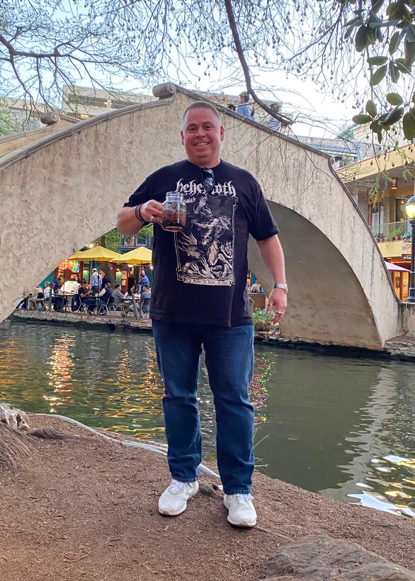 Man standing on walkway with bridge in background