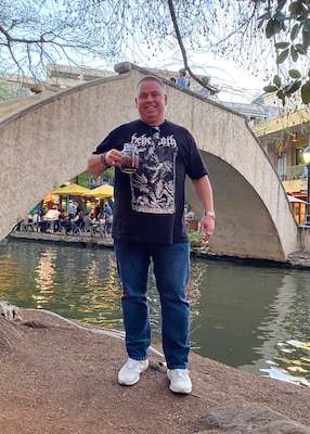 Man standing on walkway with bridge in background