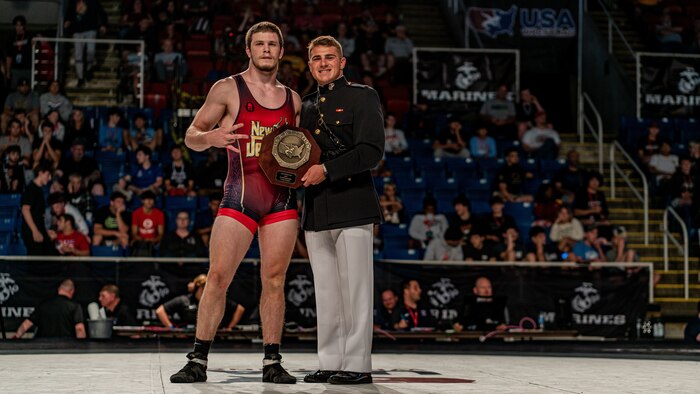U.S. Marine Corps 2nd Lt. Andrew Cerniglia, a basic officer with Marine Corps Recruiting Command, presents a first-place award (Junior) to Harvey Ludington, the National Champion, at the 2024 U.S. Marine Corps Junior & 16U Nationals in Fargo, North Dakota, July 17, 2024. The Marine Corps’ partnership with USA Wrestling started in 2017 as a way for Marines to develop new relationships with wrestling coaches. These partnerships ensure the coaches of the next generation of Marines are aware of Marine Corps opportunities, provide advocacy and support recruiter access to prospective audiences, which is critical to our nation's defense. (U.S. Marine Corps photo by Sgt. Jesse K. Carter-Powell)