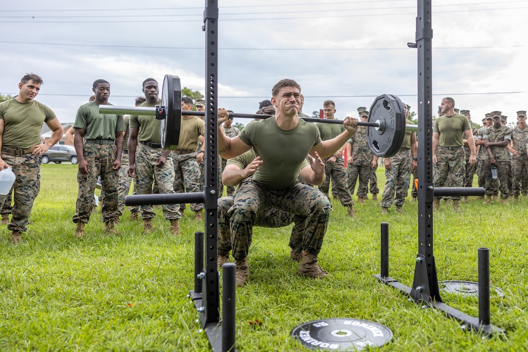 A U.S. Marine with 2nd Marine Logistics Group conducts barbell squats during the Fittest of the 2nd MLG event hosted by the 2nd MLG Human Performance Center on Camp Lejeune, North Carolina, July 19, 2024. Teams from across 2nd MLG regiments and battalions competed for the title of “Fittest of 2nd MLG” in order to promote physical fitness, camaraderie, and friendly competition. (U.S. Marine Corps photo by Lance Cpl. Christian Salazar)