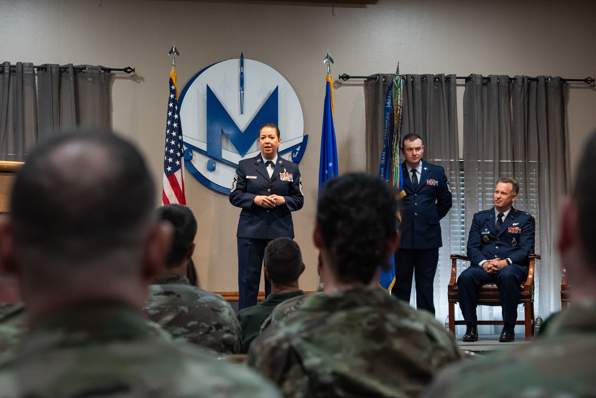 U.S. Air Force Chief Master Sgt. Becky Thomas, 91st Missile Wing command chief (center), speaks to the crowd at an assumption of responsibility ceremony at Minot Air Force Base, North Dakota, July 19, 2024. Thomas spoke about her excitement and enthusiasm for the opportunity to lead the 91st Missile Wing’s Airmen. (U.S. Air Force photo by Senior Airman Kyle Wilson)