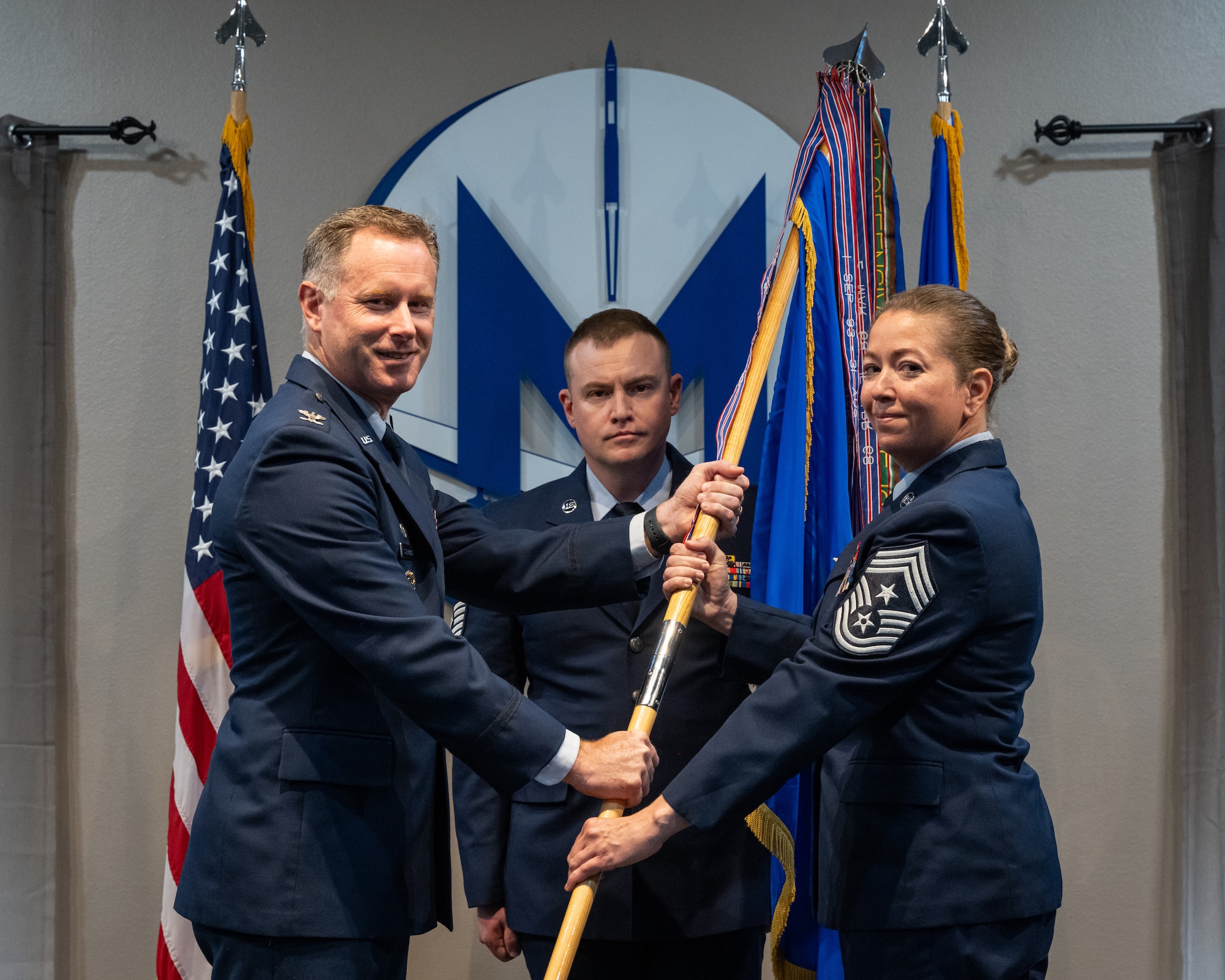 U.S. Air Force Col. James Schlabach, 91st Missile Wing commander (left), passes a guidon to Chief Master Sgt. Becky Thomas, 91st Missile Wing command chief, during an assumption of responsibility ceremony at Minot Air Force Base, North Dakota, July 19, 2024. The passing of the guidon symbolized the assumption of responsibility by Thomas as the command chief of the 91st Missile Wing. (U.S. Air Force photo by Senior Airman Kyle Wilson)