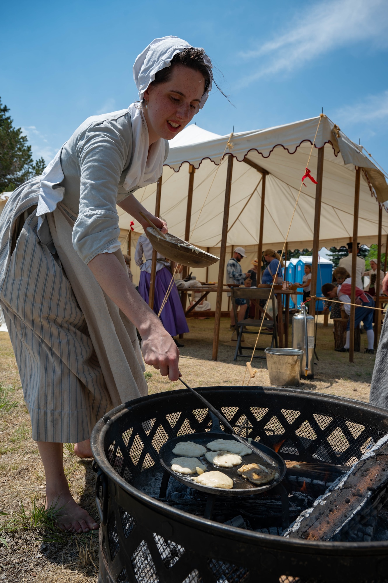 A historical reenactor cooks over a fire.