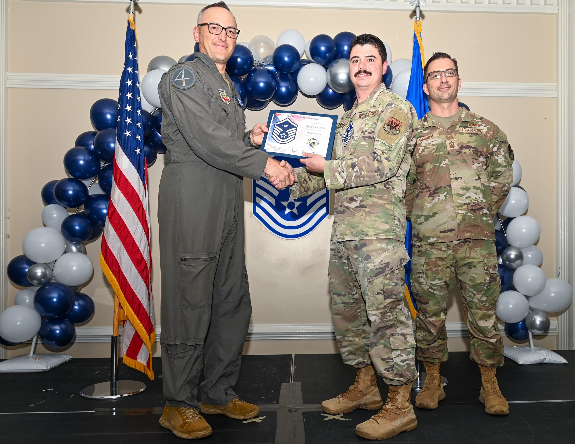 U.S. Air Force Col. Steven Bofferding, 4th Fighter Wing deputy commander (left), and Chief Master Sgt. Paul Hammer, 4 FW command chief, present a certificate to Master Sgt. select Robert Davila (center), 4th Operations Support Squadron non-commissioned officer in charge of aircrew flight equipment mobility, during a Master Sergeant Release Ceremony at Seymour Johnson Air Force Base, North Carolina, June 6, 2024. A total of 5,500 Airmen were promoted among a pool of 29,497 across the Air Force. (U.S. Air Force photo by Airman Rebecca Tierney)