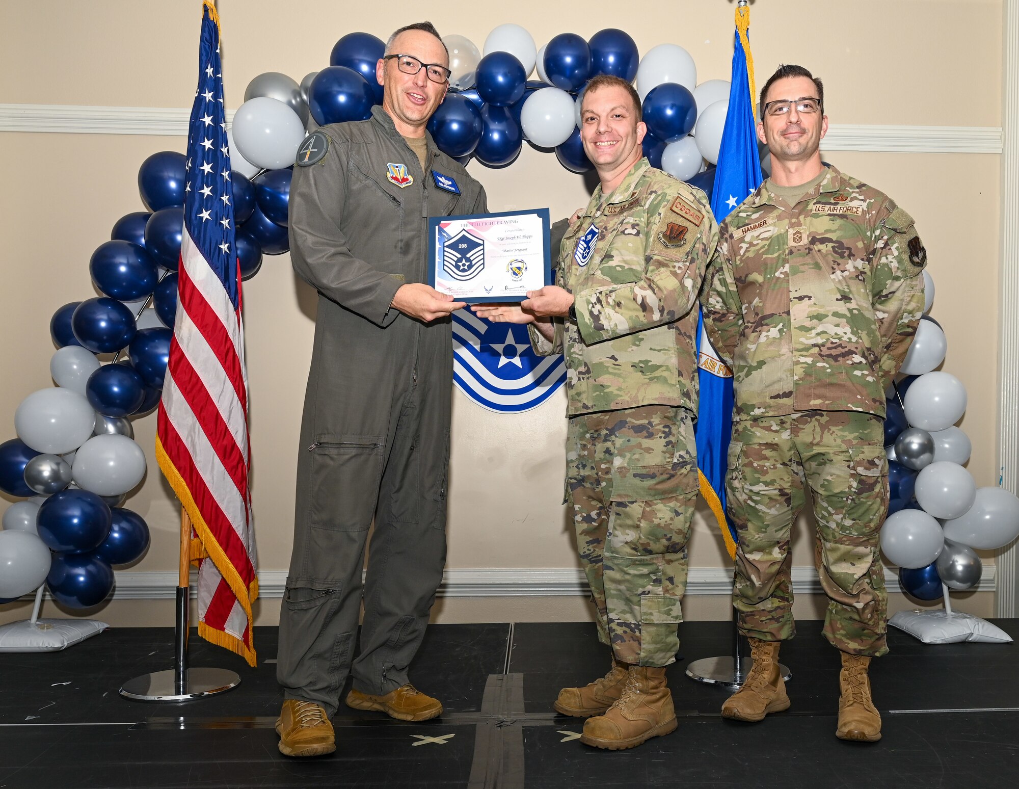 U.S. Air Force Col. Steven Bofferding, 4th Fighter Wing deputy commander (left), and Chief Master Sgt. Paul Hammer, 4 FW command chief, present a certificate to Master Sgt. select Joseph Phipps (center), 4th Equipment Maintenance Squadron crashed, damaged, and disabled aircraft recovery section chief, during a Master Sergeant Release Ceremony at Seymour Johnson Air Force Base, North Carolina, June 6, 2024. A total of 5,500 Airmen were promoted among a pool of 29,497 across the Air Force. (U.S. Air Force photo by Airman Rebecca Tierney)