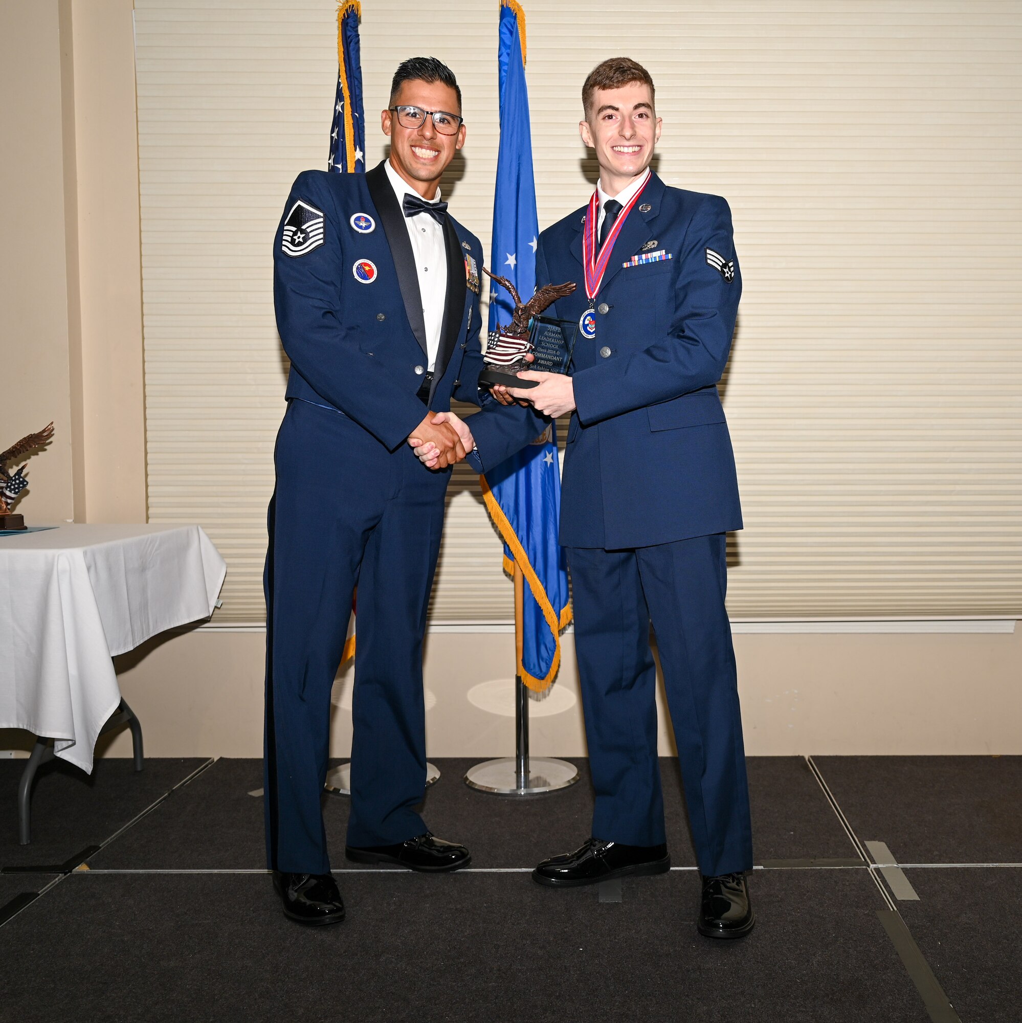U.S. Air Force Senior Airman Bryce Johnson, 336th Fighter Generation Squadron stockpile management technician, right, accepts the Commandant’s Award from Master Sgt. Mark Benevides, Airman Leadership School instructor, during the ALS class 24-E graduation ceremony at Seymour Johnson Air Force Base, North Carolina, June 27, 2024. The Commandant’s Award is presented to an ALS graduate that possessed the highest degree of character, competence, and commitment during the ALS course. (U.S. Air Force photo by Airman Rebecca Tierney)