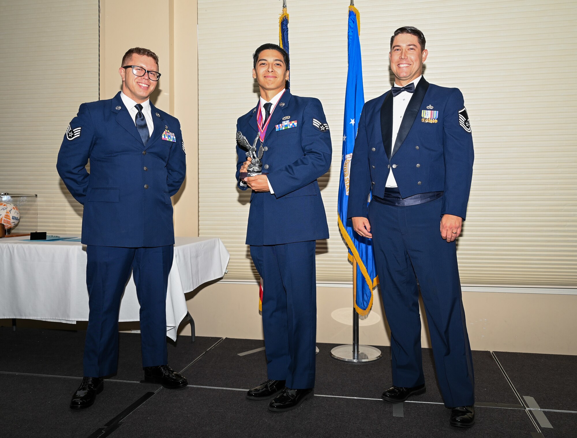 U.S. Air Force Senior Airman Jacob Islas, 4th Component Maintenance Squadron avionics technician, center, accepts the Distinguished Graduate Award from Staff Sgt. Joshua Irwin, left, 4th Operations Support Squadron wing scheduling non-commissioned officer in charge and Master Sgt. Nicolas Lamonica, 335th Fighter Generation Squadron  specialist section chief, during the ALS class 24-E graduation ceremony at Seymour Johnson Air Force Base, North Carolina, June 27, 2024. Students awarded the Distinguished Graduate Award displayed effective teamwork, academic excellence and leadership skills. (U.S. Air Force photo by Airman Rebecca Tierney)