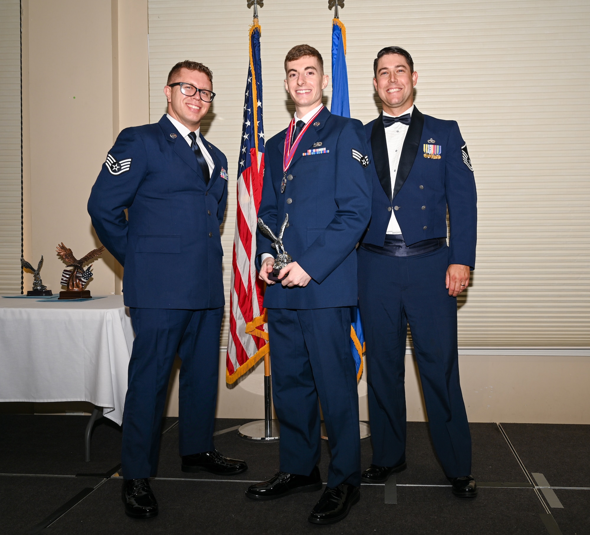 U.S. Air Force Senior Airman Bryce Johnson, 336th Fighter Generation Squadron stockpile management technician, center, accepts the Distinguished Graduate Award from Staff Sgt. Joshua Irwin, left, 4th Operations Support Squadron wing scheduling non-commissioned officer in charge and Master Sgt. Nicolas Lamonica, 335th Fighter Generation Squadron specialist section chief,  during the ALS class 24-E graduation ceremony at Seymour Johnson Air Force Base, North Carolina, June 27, 2024. Students awarded the Distinguished Graduate Award displayed effective teamwork, academic excellence and leadership skills. (U.S. Air Force photo by Airman Rebecca Tierney)