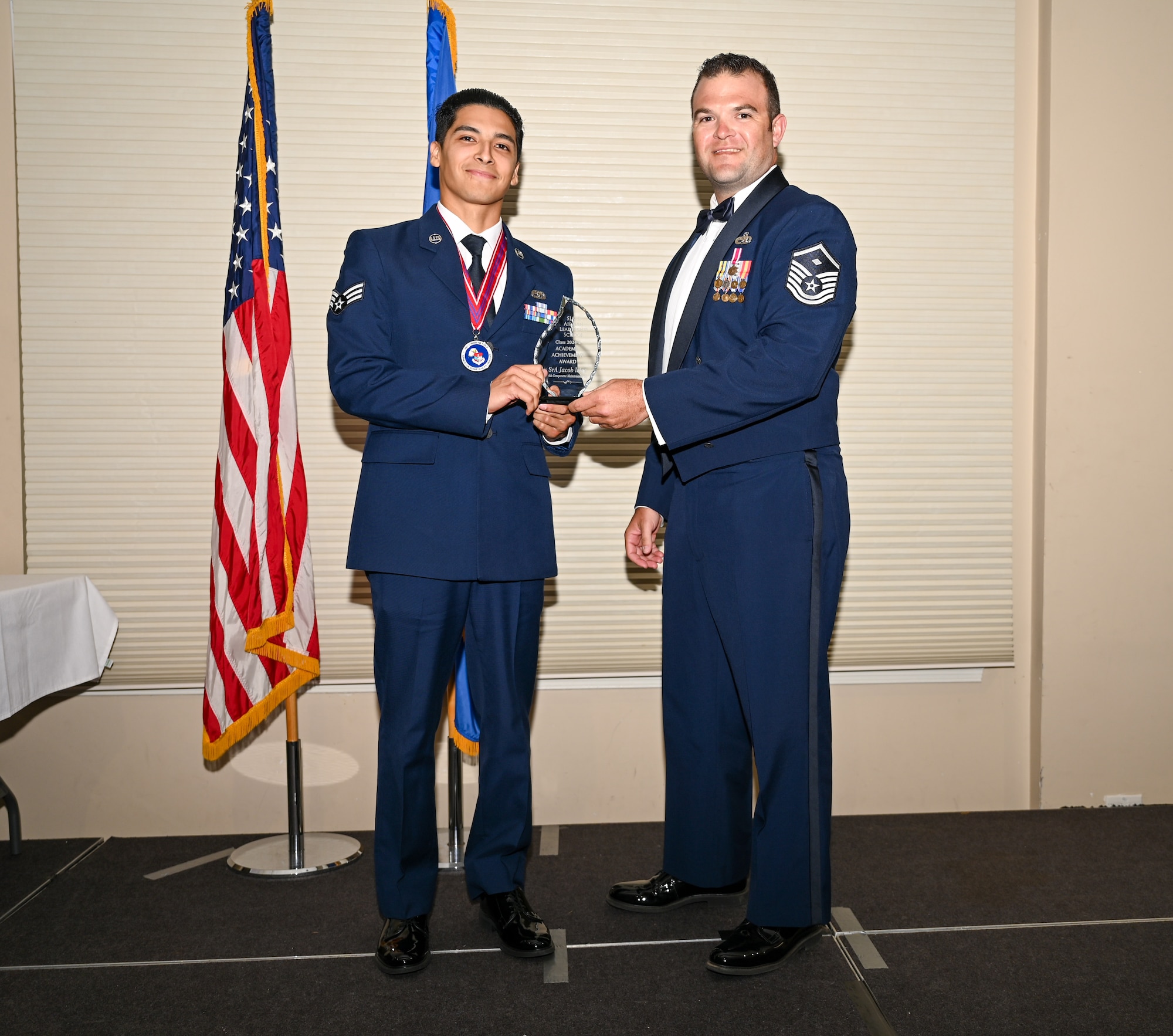 U.S. Air Force Senior Airman Jacob Islas, right, 4th Component Maintenance Squadron avionics technician, left, accepts the Academic Achievement Award from Master Sgt. Brandon Holloman, 336th Fighter Generation Squadron first sergeant, during the ALS class 24-E graduation ceremony at Seymour Johnson Air Force Base, North Carolina, June 27, 2024. The student presented with the Academic Achievement Award maintained the highest grade point average throughout the ALS course. (U.S. Air Force photo by Airman Rebecca Tierney)
