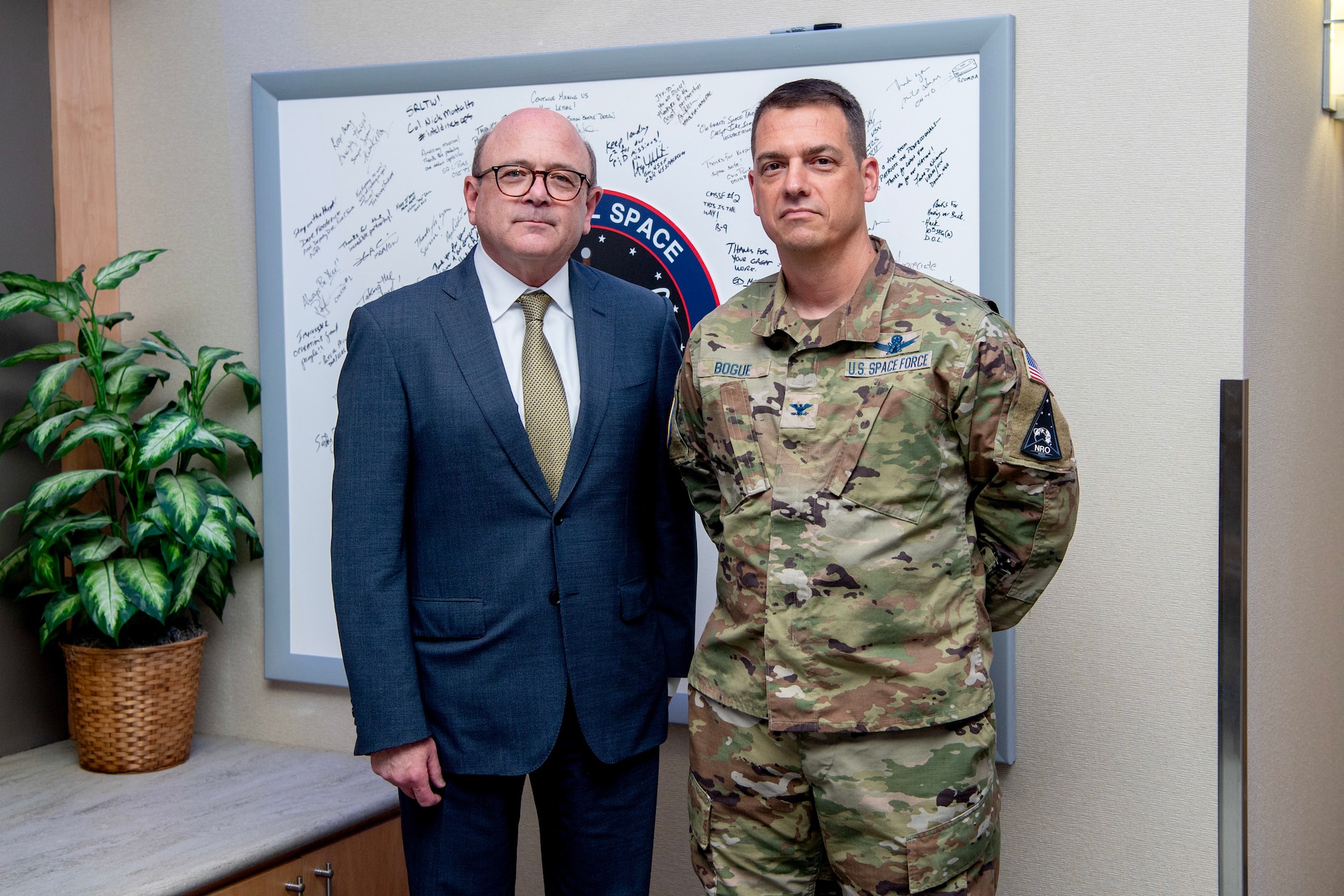 Man in suit stands next to man in military uniform