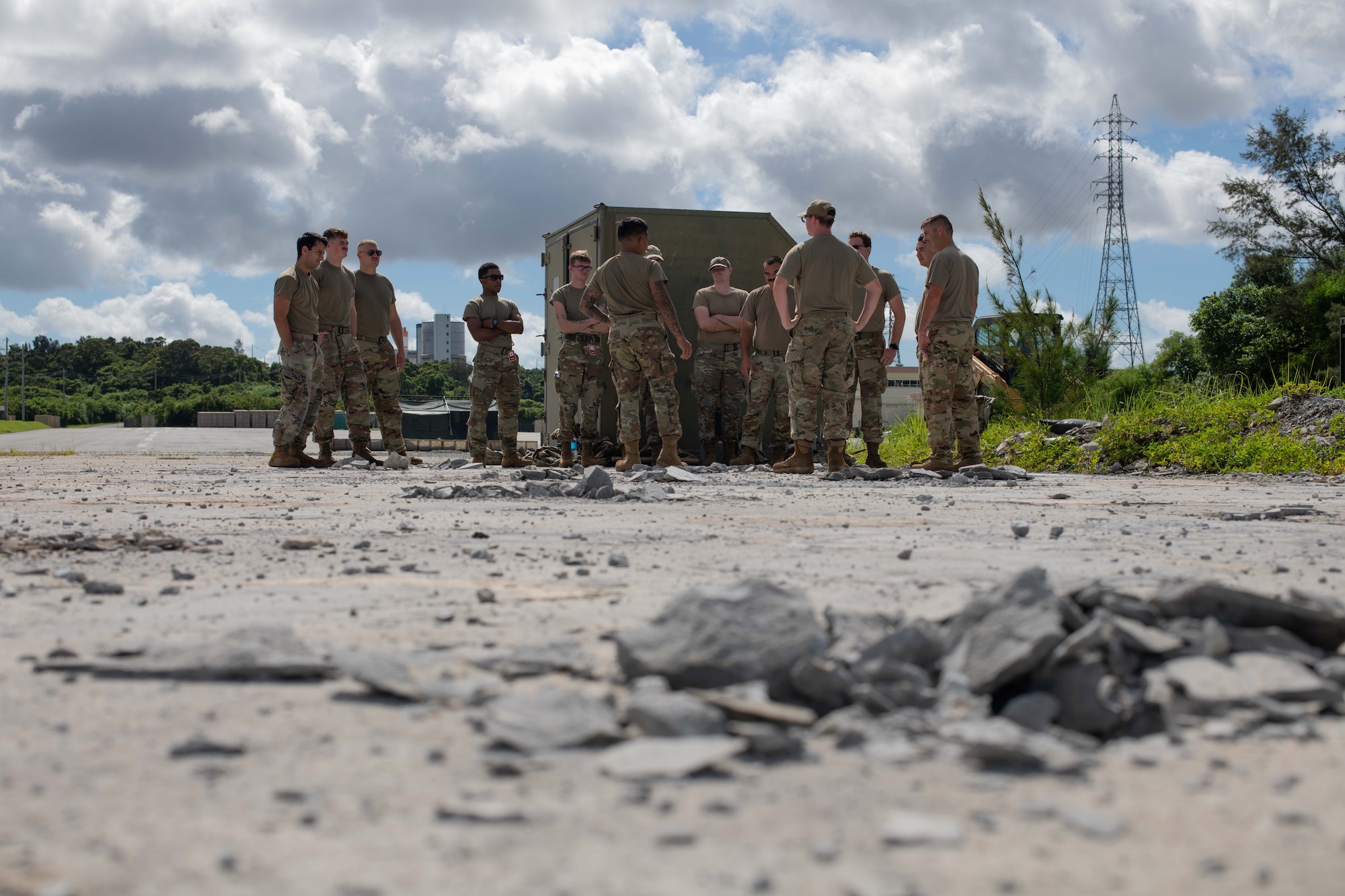 military members stand in the distance with broken concrete on the ground