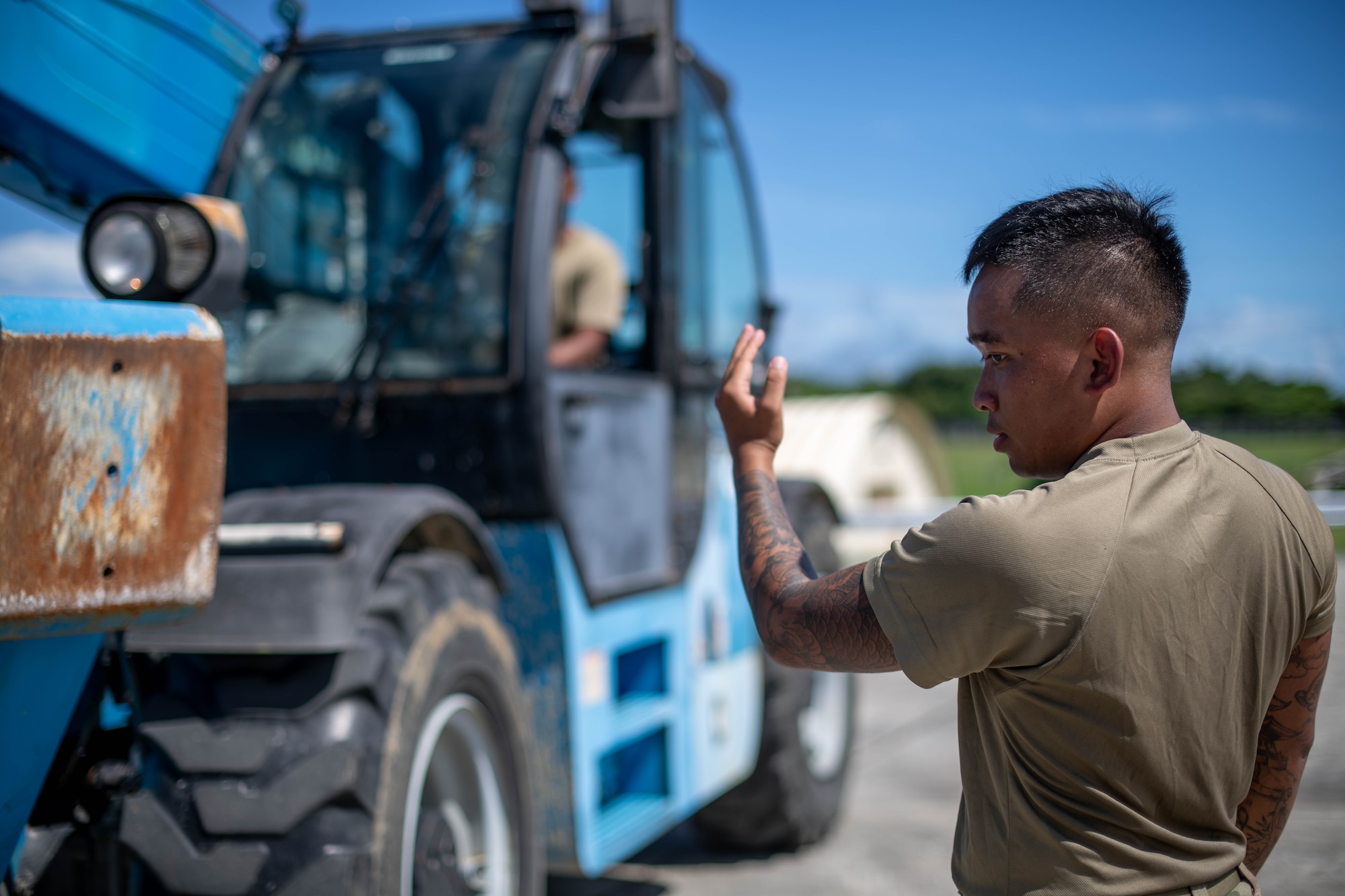 military member motions in front of a forklift