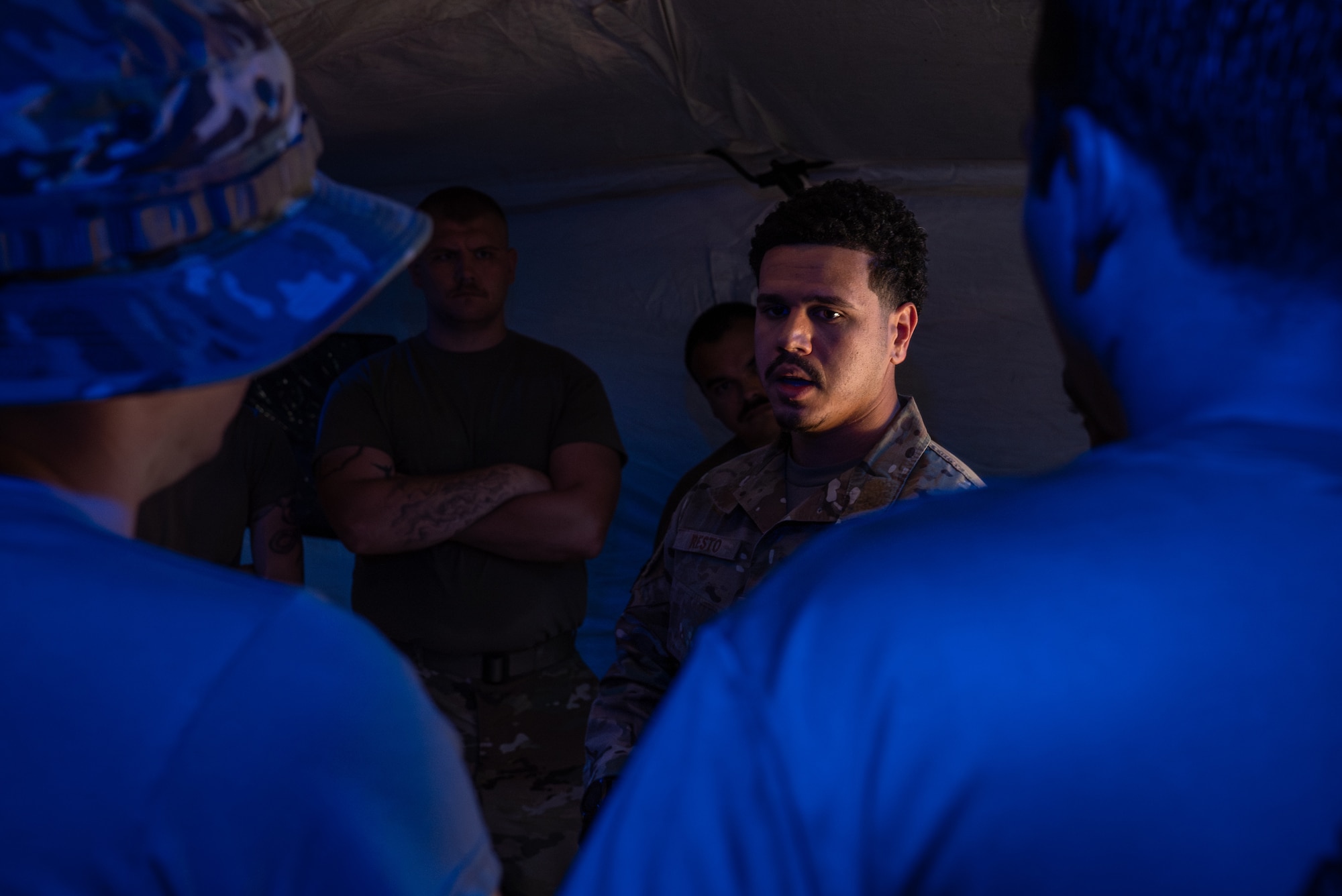 military member briefs a crowd in a low lit setting