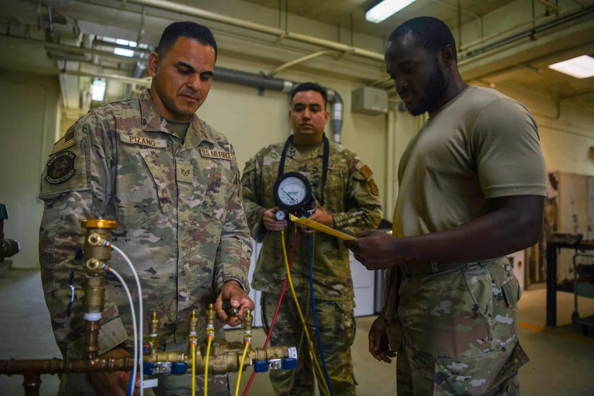Three Airmen conduct a backflow prevention device test.