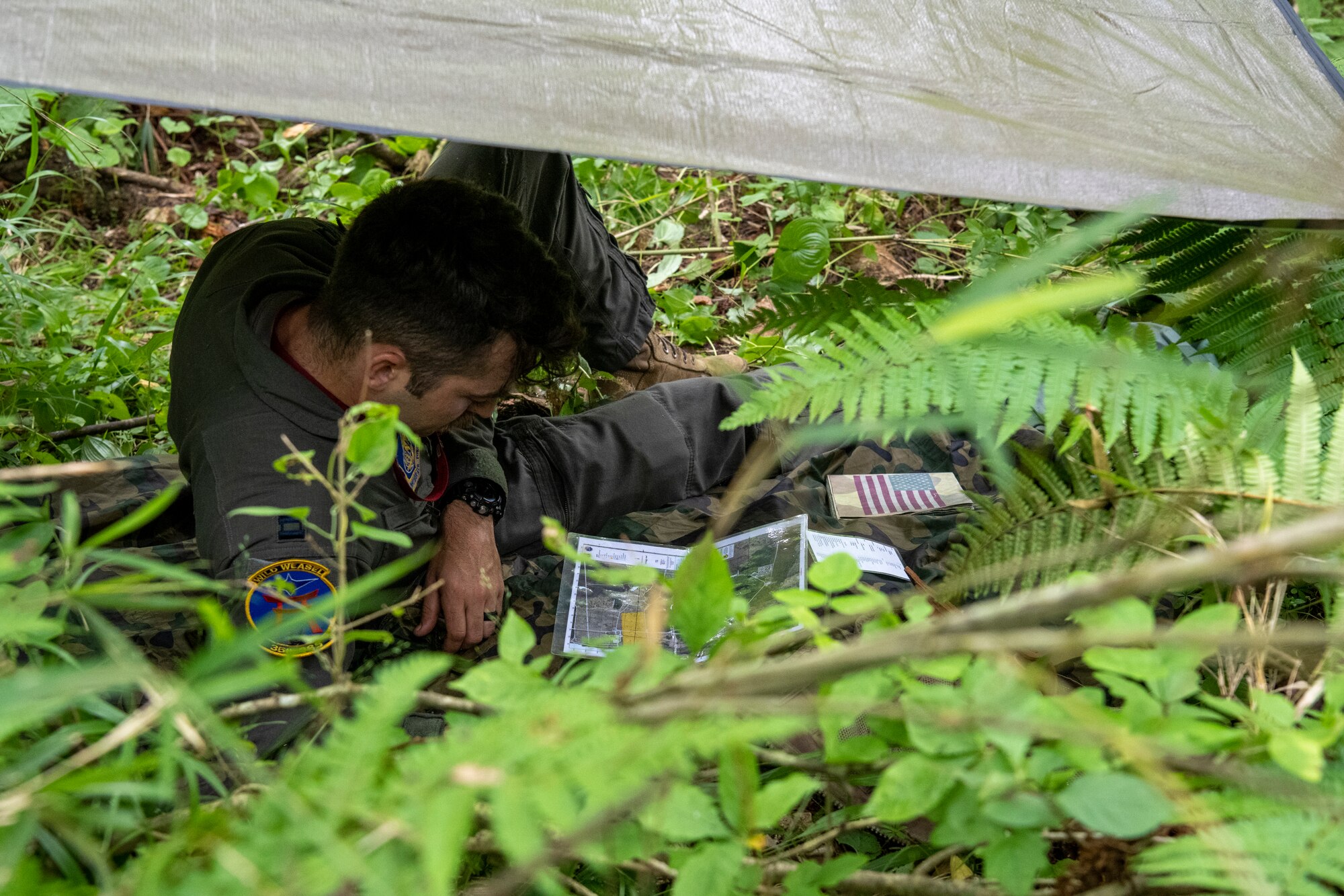 U.S. Air Force Capt. Jonathan Marshall, 35th Operations Support Squadron pilot, examines a map within a shelter during a Combat Survival Training exercise led by Survival, Evasion, Resistance, Escape (SERE) specialists at Draughon Range near Misawa Air Base, Japan, July 16, 2024.