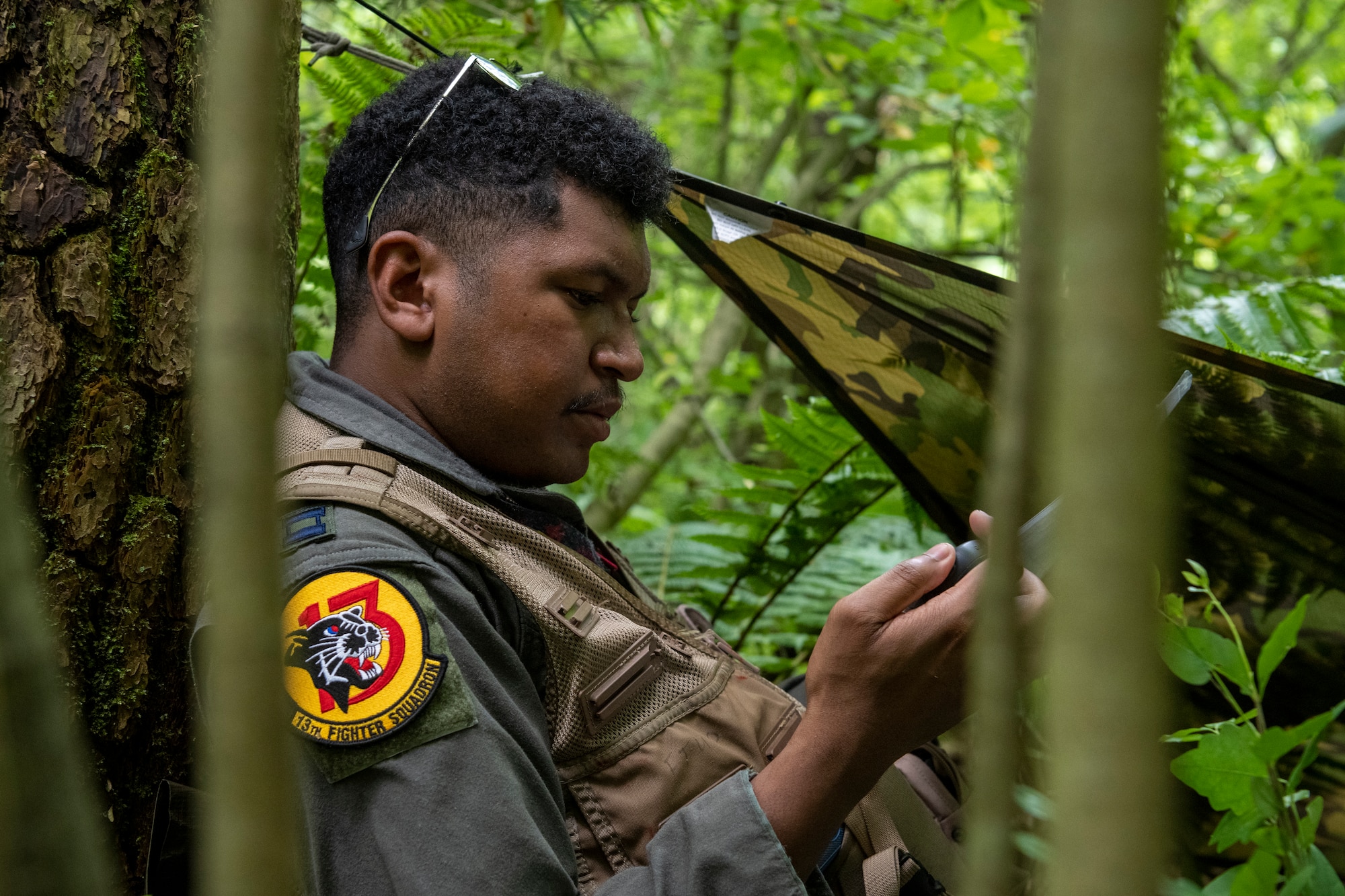 U.S. Air Force Capt. Isaiah Butcher, 13th Fighter Squadron pilot, examines a GPS during a Combat Survival Training exercise led by Survival, Evasion, Resistance, Escape (SERE) specialists at Draughon Range near Misawa Air Base, Japan, July 16, 2024.