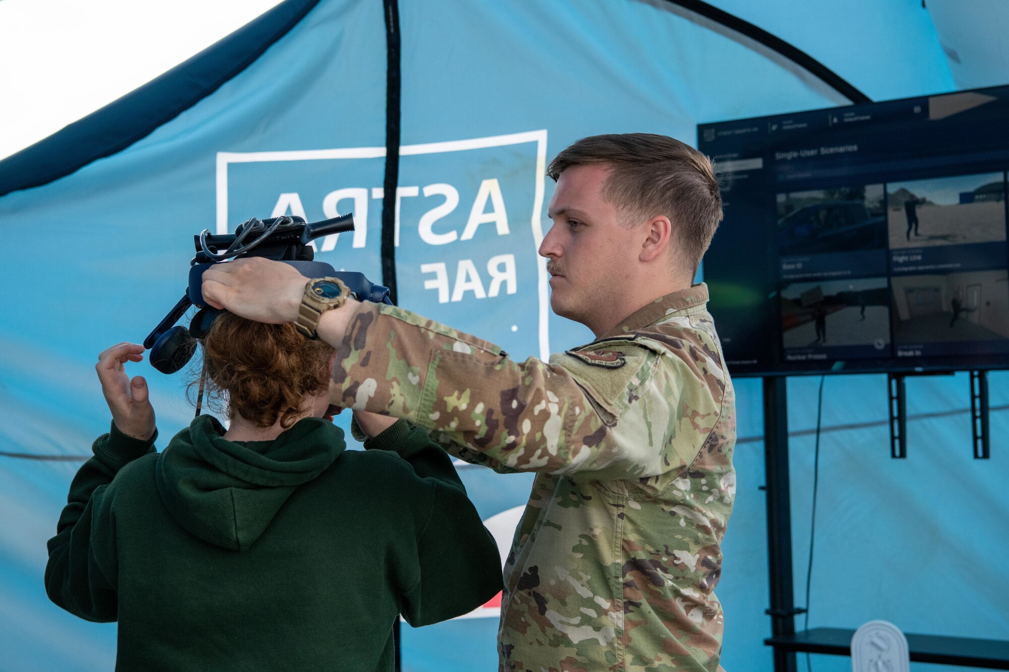 An Airman assists a participant with a virtual reality headset