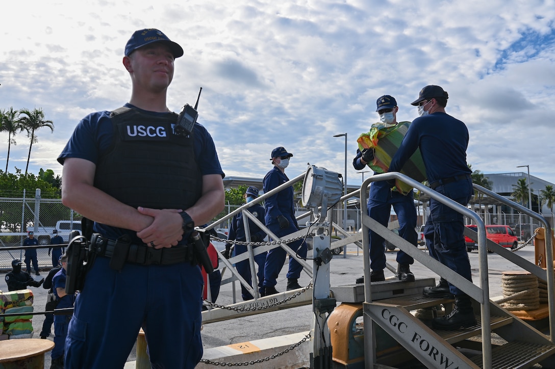 A crew member of the Coast Guard Cutter Forward standing watch over illegal narcotics, July 22, 2024, Port Everglades, Florida. Armed Coast Guardsmen stand watch over interdicted drugs to ensure security and accountability of seized contraband. (U.S. Coast Guard photo by Petty Officer 3rd Class Nicholas Strasburg)