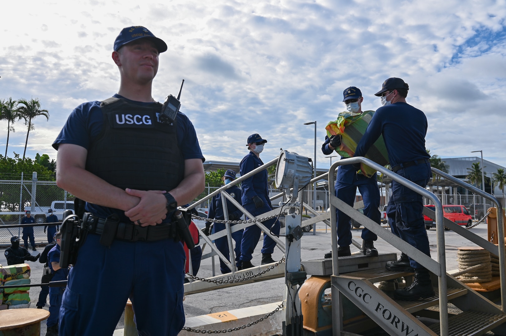 A crew member of the Coast Guard Cutter Forward standing watch over illegal narcotics, July 22, 2024, Port Everglades, Florida. Armed Coast Guardsmen stand watch over interdicted drugs to ensure security and accountability of seized contraband. (U.S. Coast Guard photo by Petty Officer 3rd Class Nicholas Strasburg)