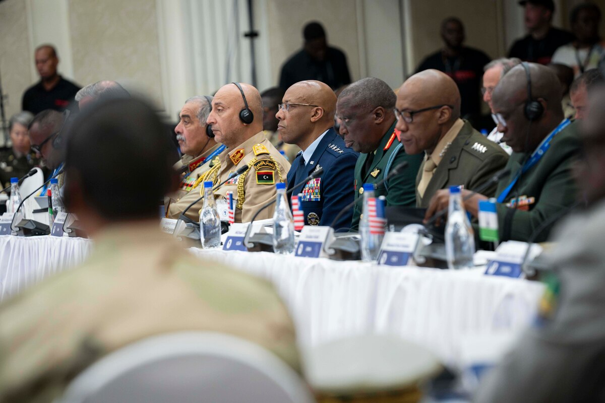 People in uniform sit at a long conference table.