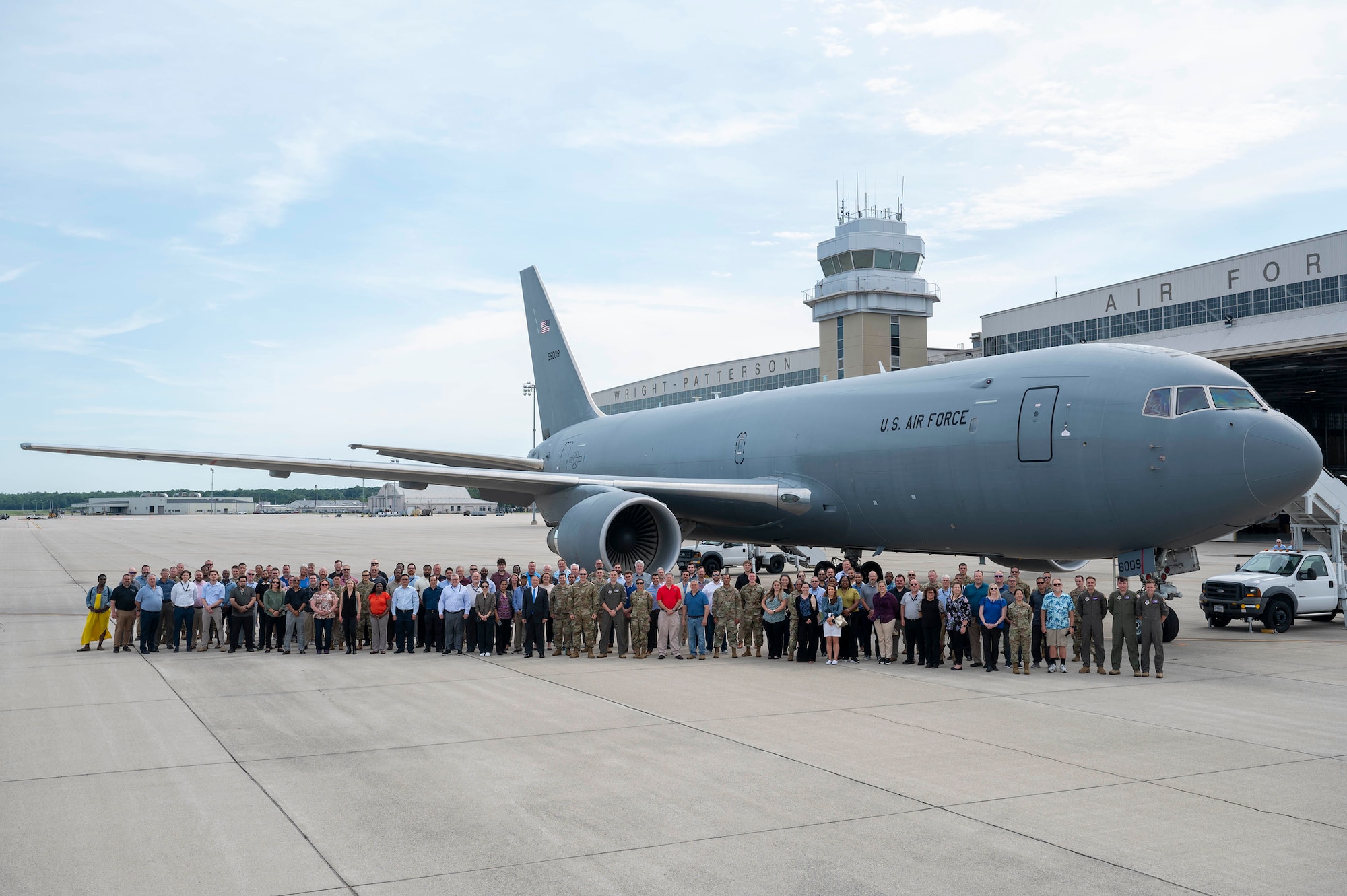 Group of Air Force uniformed and civilian employees stand in front of KC-46A airframe.