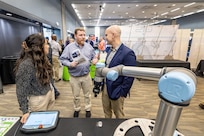 Gina Kim, of Olympus Controls, talks about robot technology with Mathew Cady, product line director, Code 1000, Production Line Department, and Steve McKee, director of Enterprise Maintenance Technologies Sept. 27, 2023, during the Puget Sound Naval Shipyard & Intermediate Maintenance Facility Technology Showcase at the Kitsap Conference Center in Bremerton, Washington. This year's event is scheduled for July 31-Aug. 1. (U.S. Navy photo by Jeb Fach)