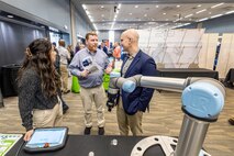 Gina Kim, of Olympus Controls, talks about robot technology with Mathew Cady, product line director, Code 1000, Production Line Department, and Steve McKee, director of Enterprise Maintenance Technologies Sept. 27, 2023, during the Puget Sound Naval Shipyard & Intermediate Maintenance Facility Technology Showcase at the Kitsap Conference Center in Bremerton, Washington. This year's event is scheduled for July 31-Aug. 1. (U.S. Navy photo by Jeb Fach)